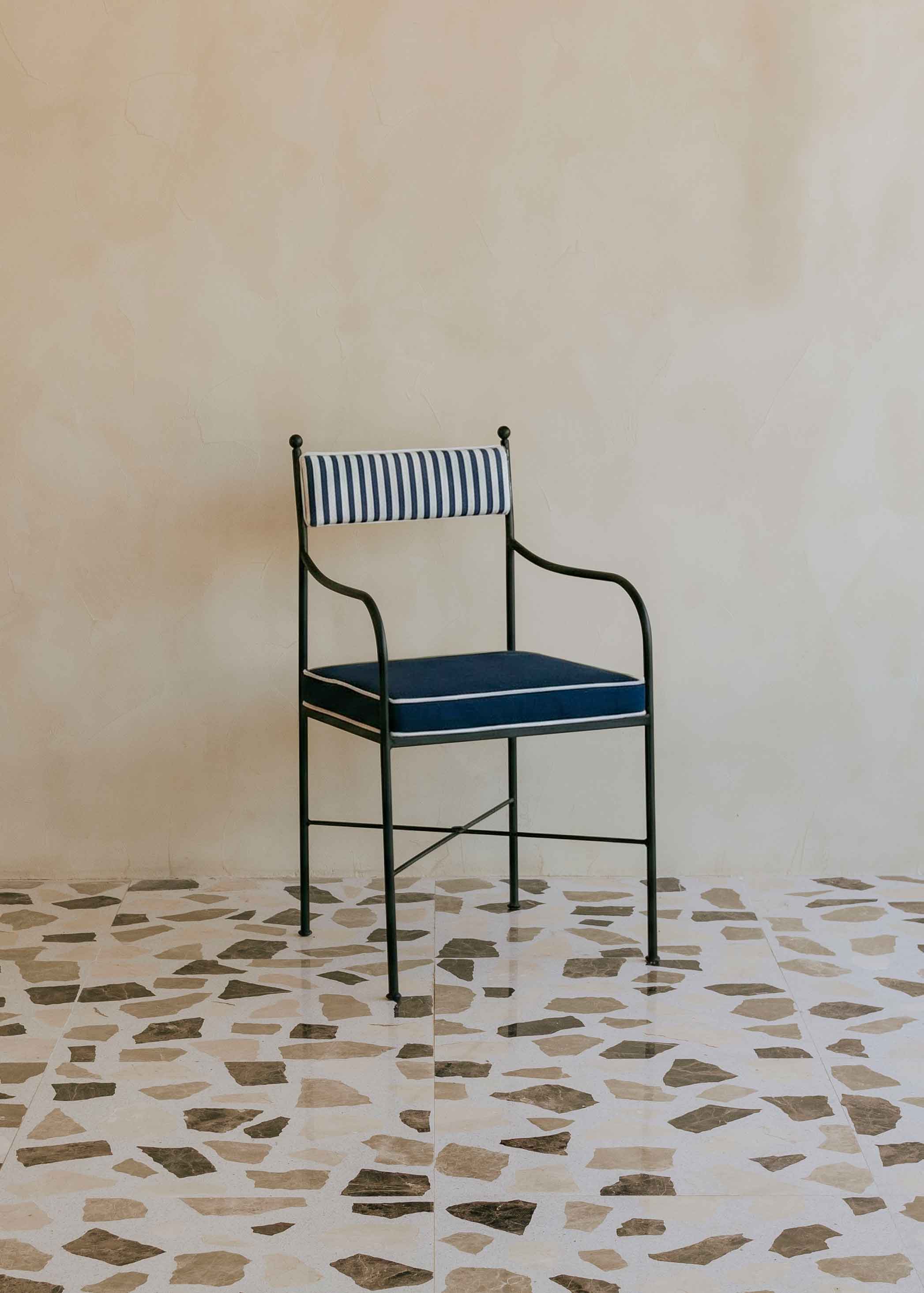 Silla de exterior con estructura de hierro negro tapizada en azul marino y blanco.