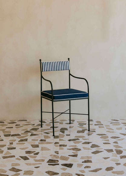 Silla de exterior con estructura de hierro negro tapizada en azul marino y blanco.