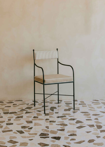 Silla de exterior con estructura de hierro negro tapizada en beige y blanco.