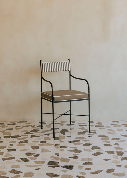 Silla de exterior con estructura de hierro negro tapizada en color topo y blanco.