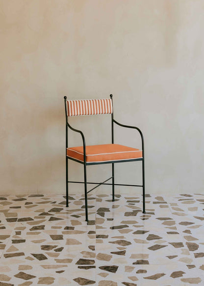 Silla de exterior con estructura de hierro negro tapizada en naranja y blanco.