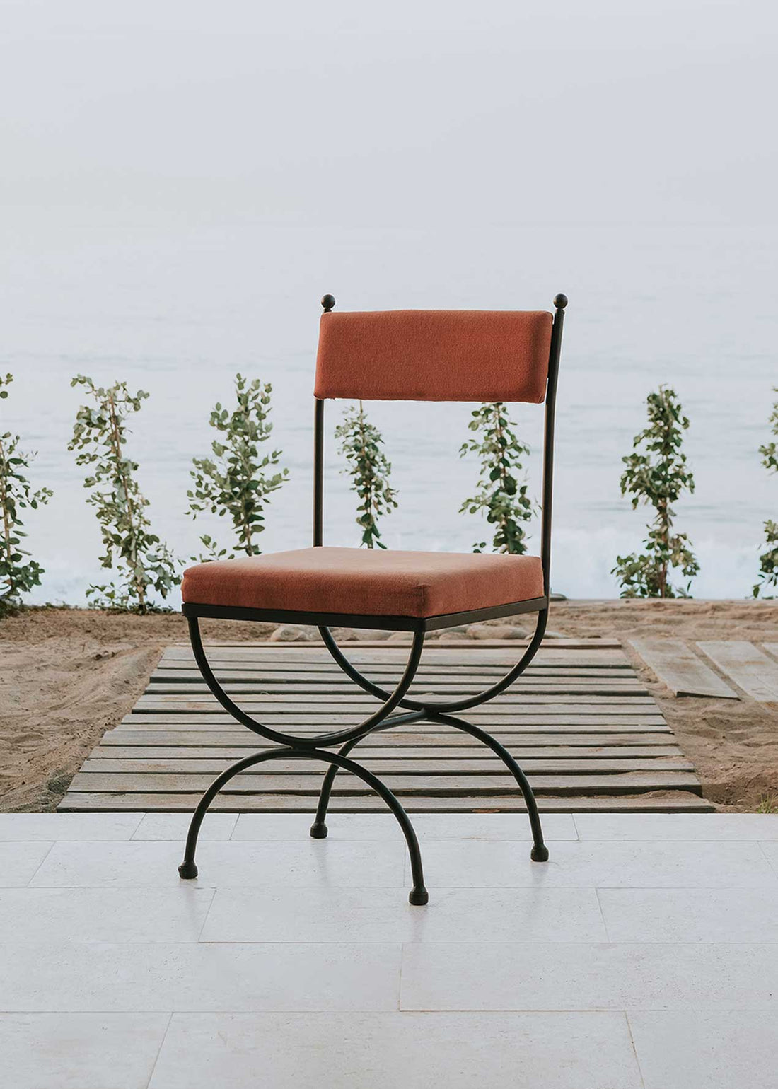 Silla de exterior con estructura de hierro forjado negro tapizada en color caldero.