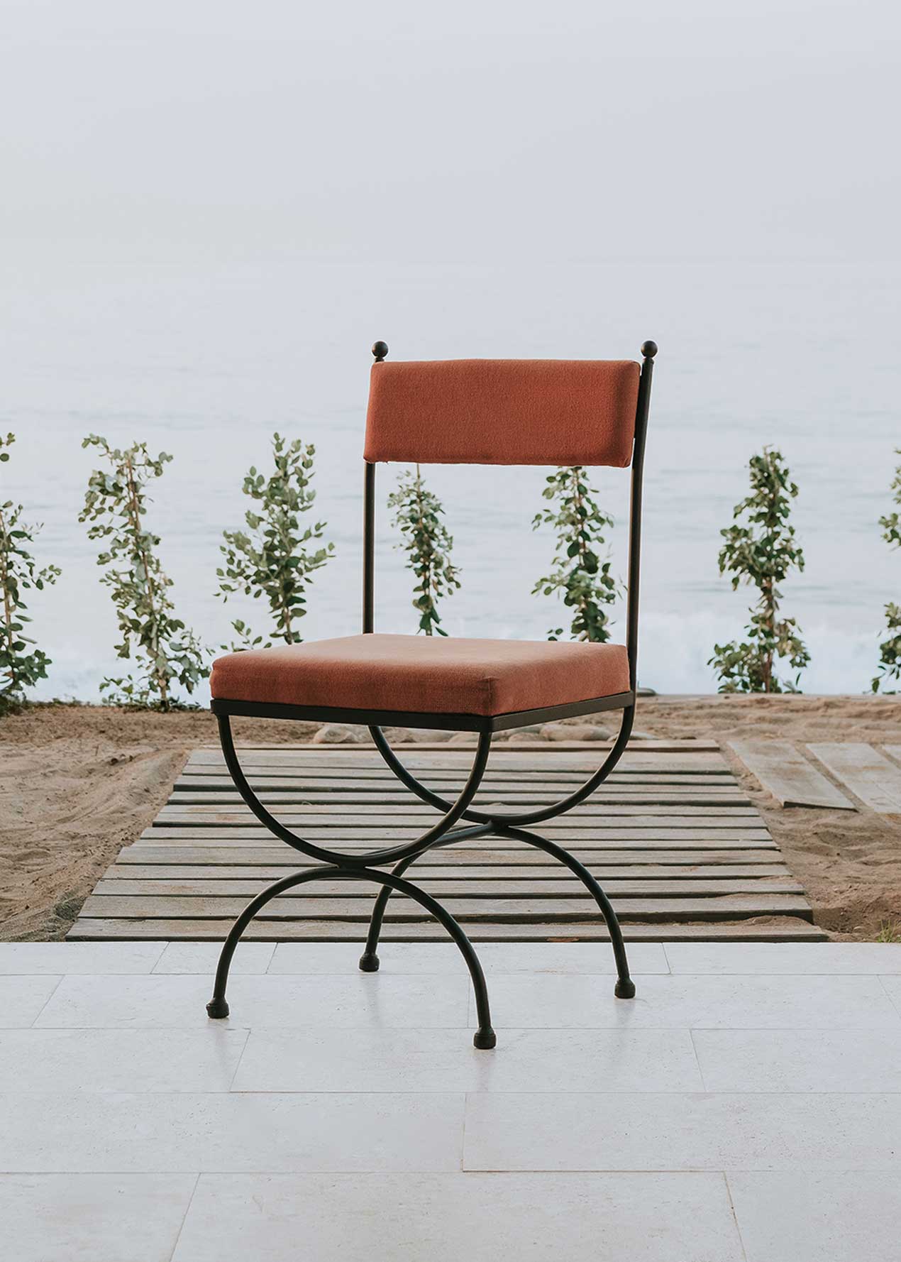 Silla de exterior con estructura de hierro forjado negro tapizada en color caldero.