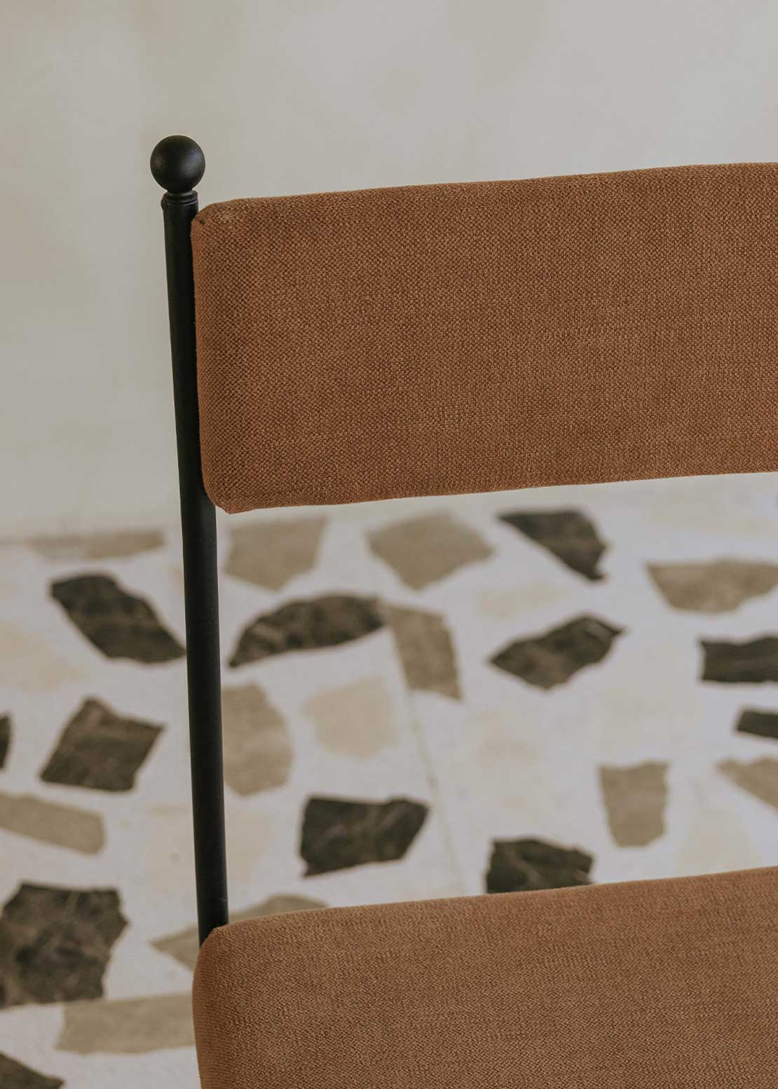 Silla de exterior con estructura de hierro forjado negro tapizada en color caldero.