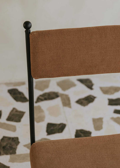 Silla de exterior con estructura de hierro forjado negro tapizada en color caldero.