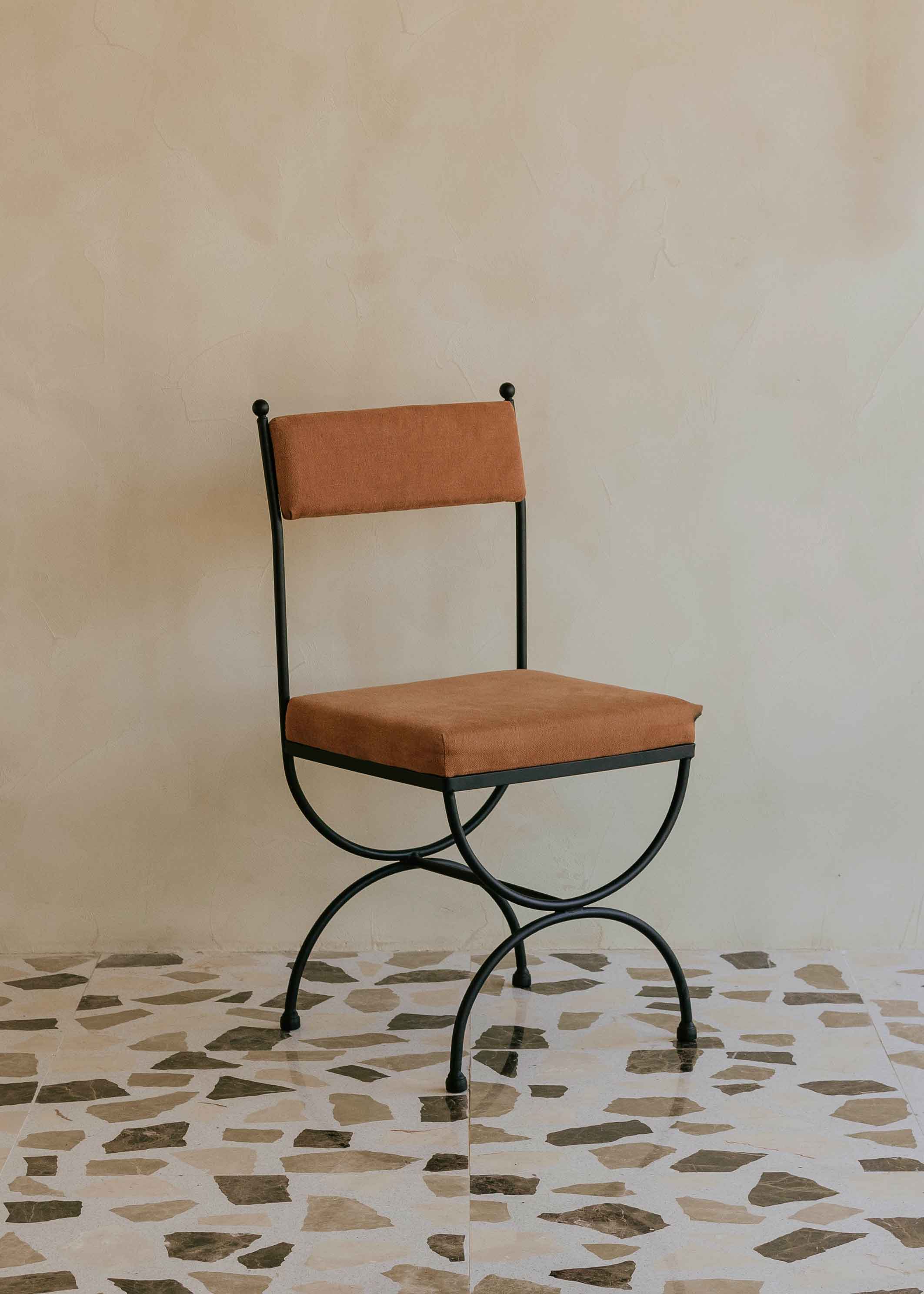 Silla de exterior con estructura de hierro negro tapizada en color caldero.