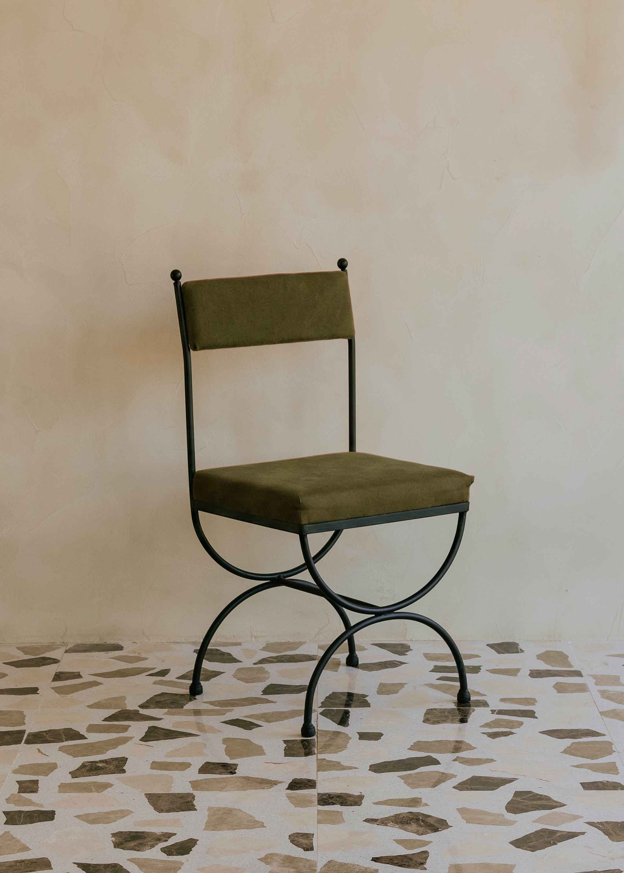 Silla de exterior con estructura de hierro negro tapizada en color verde musgo.