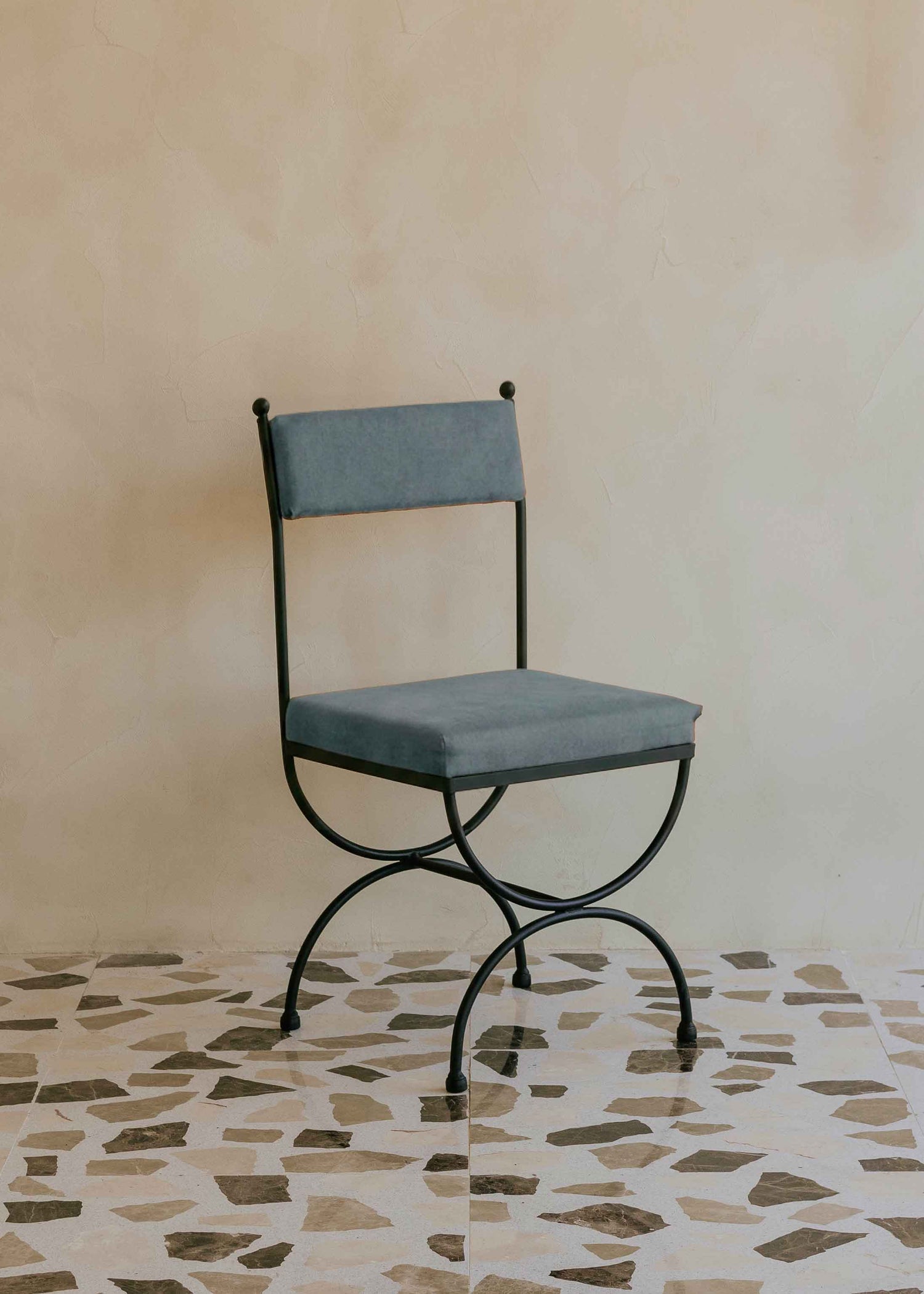 Silla de exterior con estructura de hierro negro tapizada en color azul jaspeado.