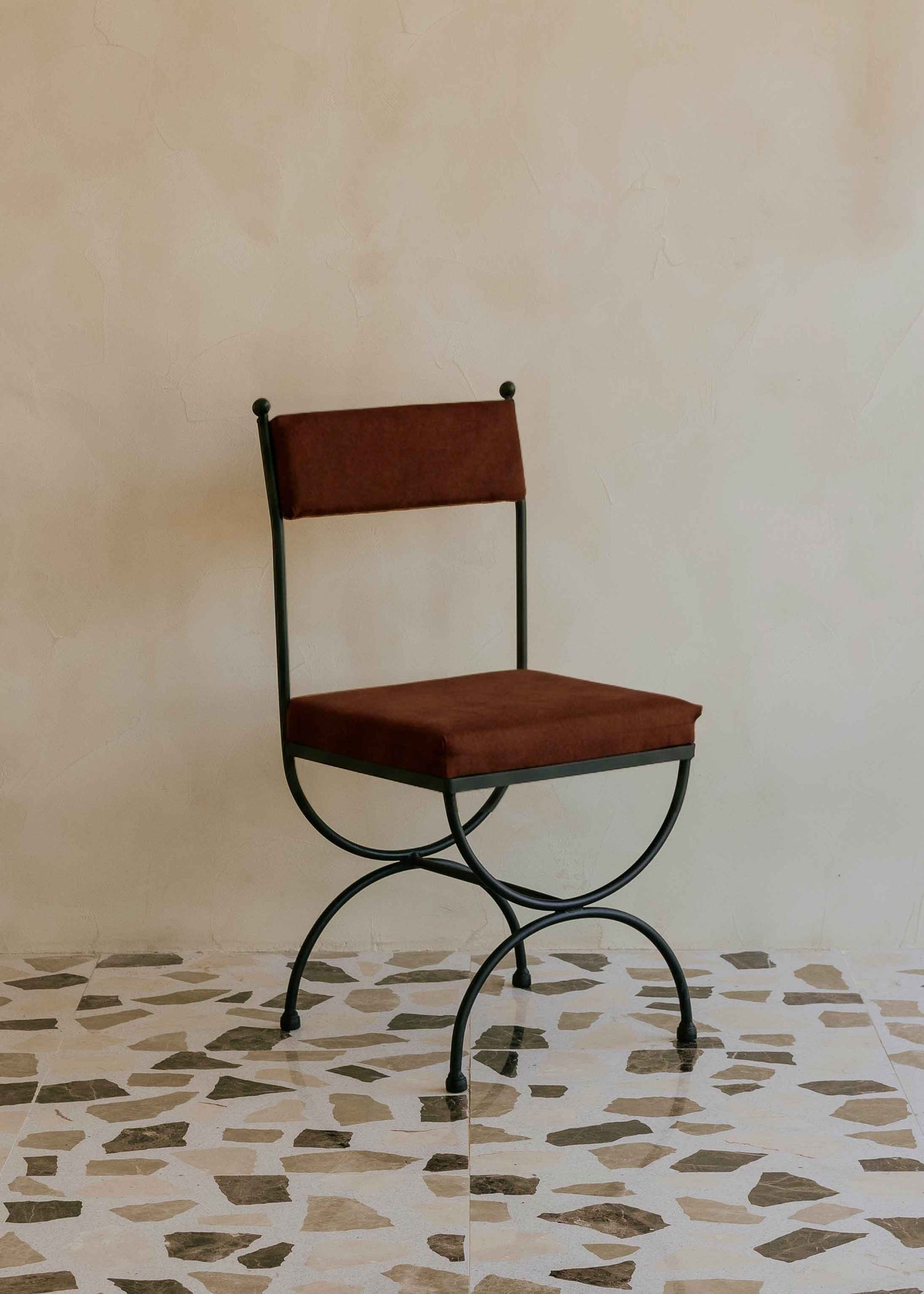 Silla de exterior con estructura de hierro negro tapizada en color óxido.