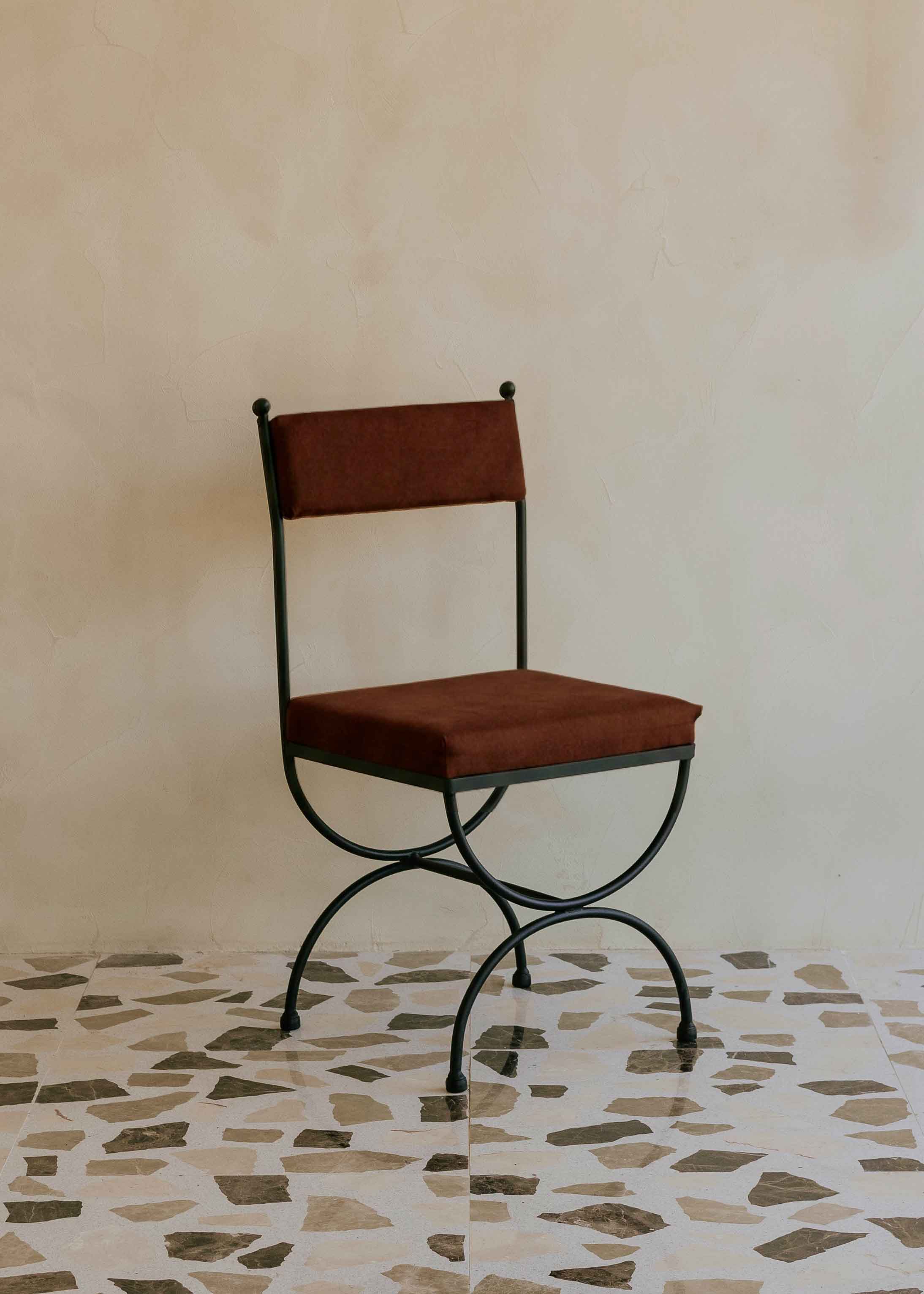 Silla de exterior con estructura de hierro negro tapizada en color óxido.