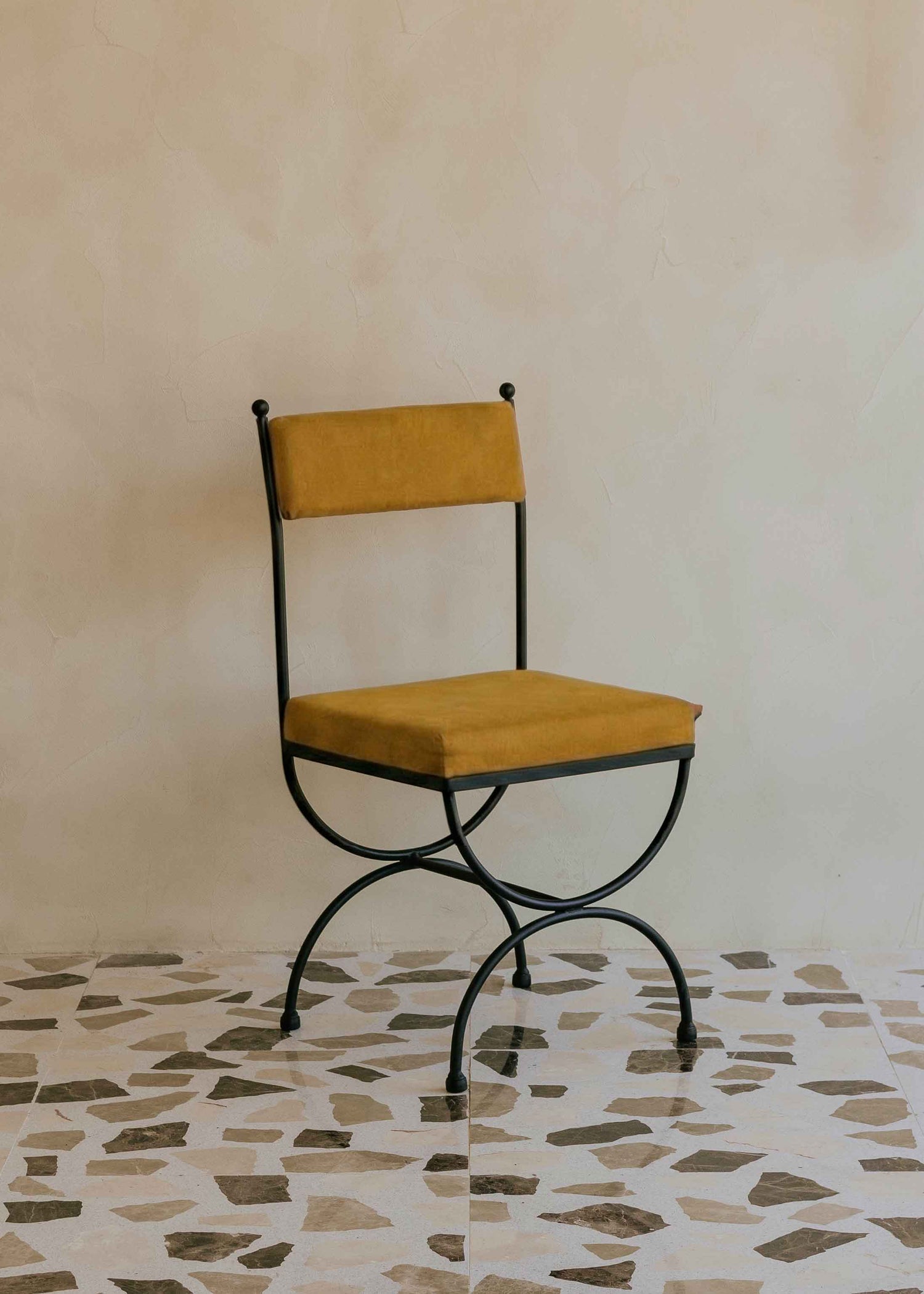 Silla de exterior con estructura de hierro negro tapizada en color mostaza.