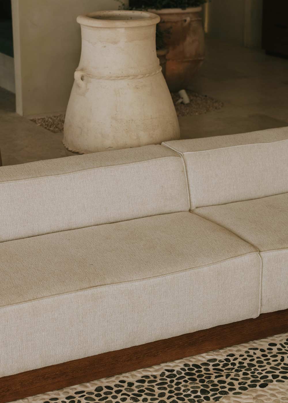 Sofá beige modular con zócalo en madera