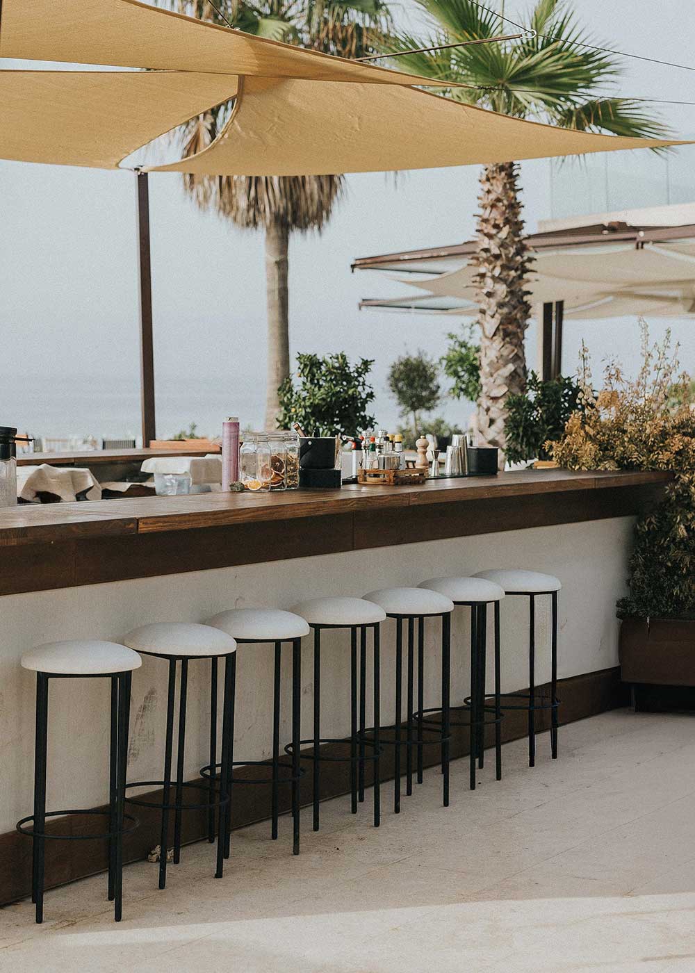 Taburete con estructura de hierro acabado en negro tapizado en tela blanca.