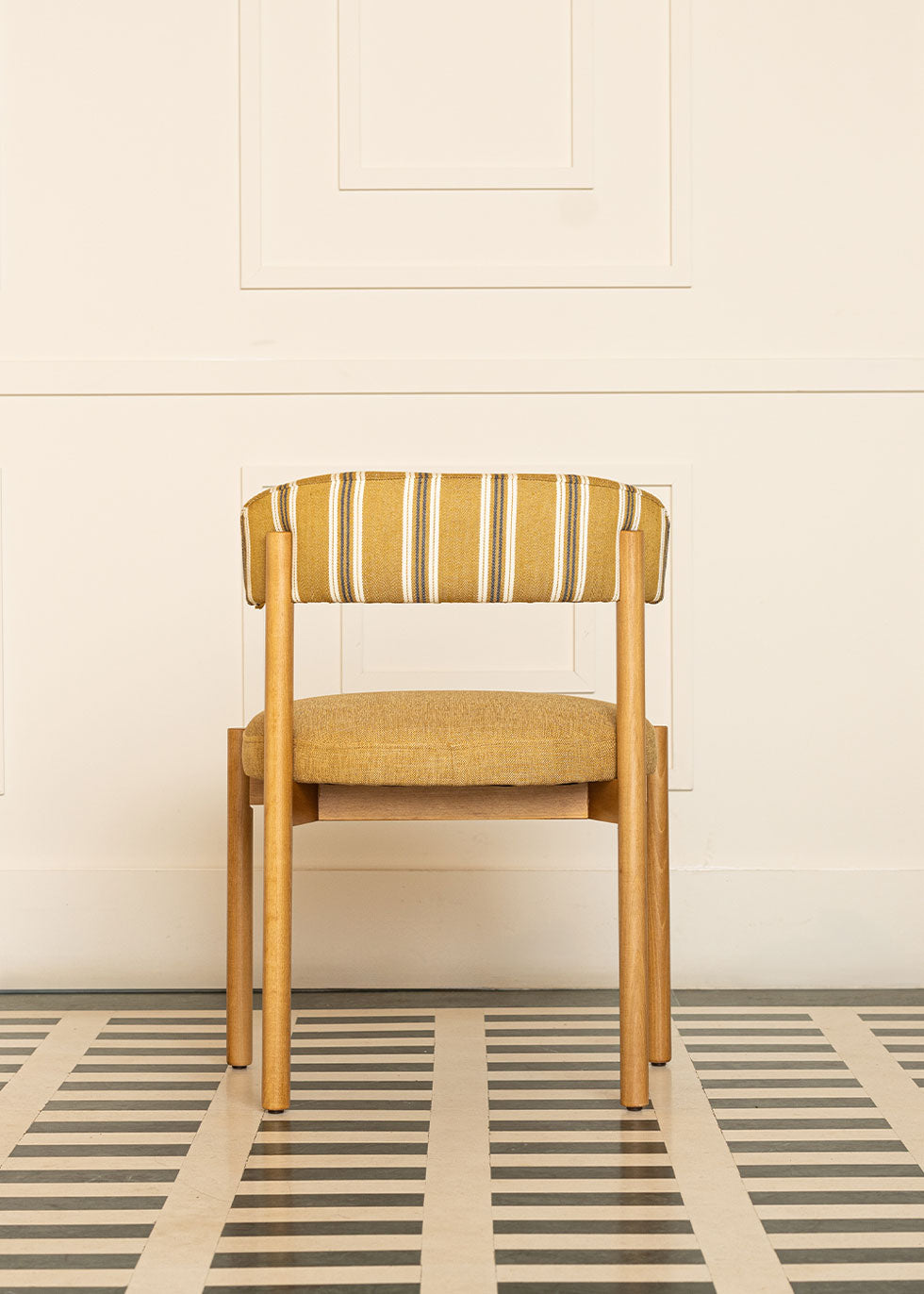 Silla de madera de haya con asiento tapizado en tela mostaza y respaldo con estampado de rayas.