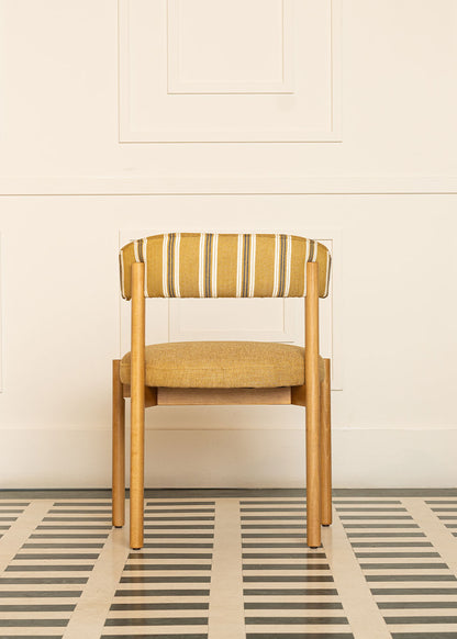 Silla de madera de haya con asiento tapizado en tela mostaza y respaldo con estampado de rayas.