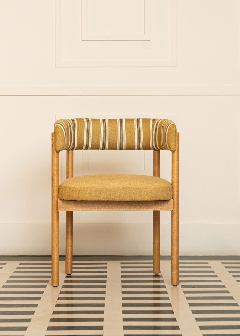 Silla de madera de haya con reposabrazos, asiento tapizado en tela mostaza y respaldo con estampado de rayas.