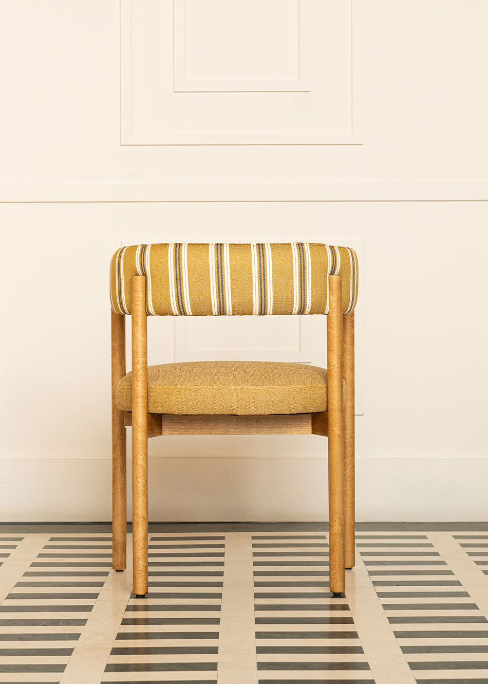 Silla de madera de haya con reposabrazos, asiento tapizado en tela mostaza y respaldo con estampado de rayas.