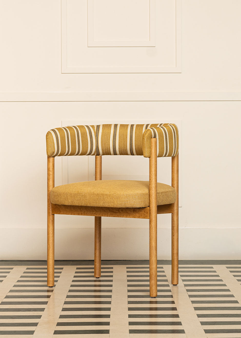 Silla de madera de haya con reposabrazos, asiento tapizado en tela mostaza y respaldo con estampado de rayas.