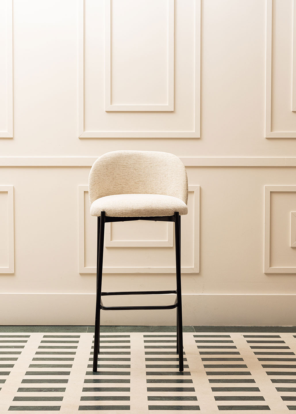 Taburete tapizado en tela beige con estructura de hierro acabado en negro