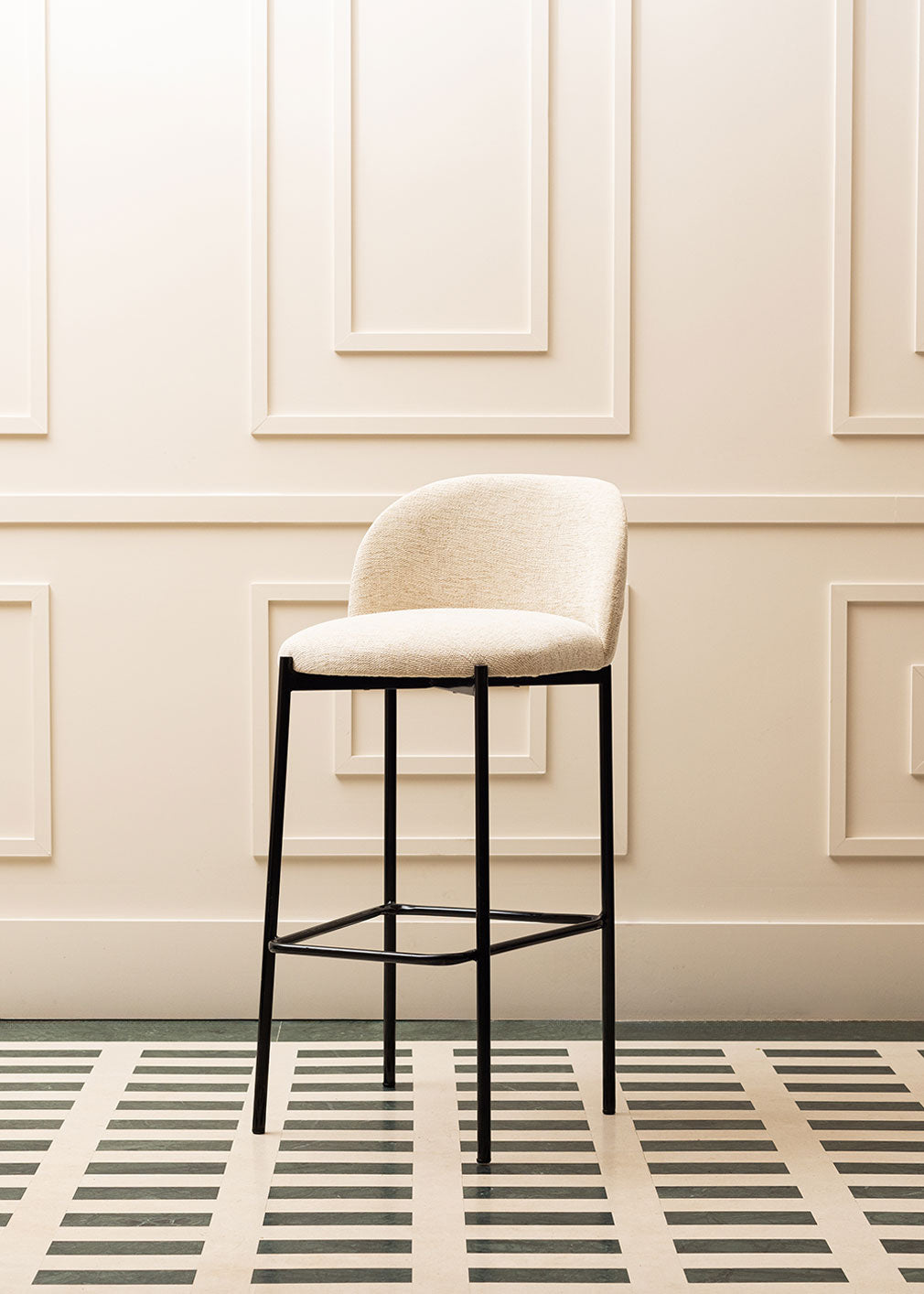 Taburete tapizado en tela beige con estructura de hierro acabado en negro