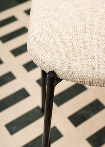 Taburete tapizado en tela beige con estructura de hierro acabado en negro