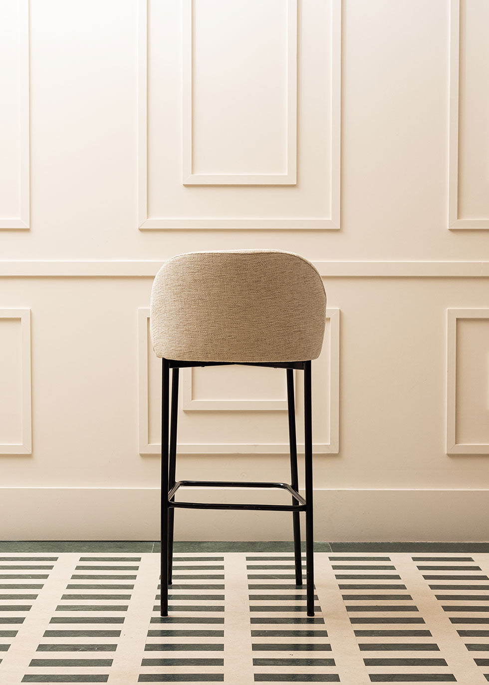 Taburete tapizado en tela beige con estructura de hierro acabado en negro