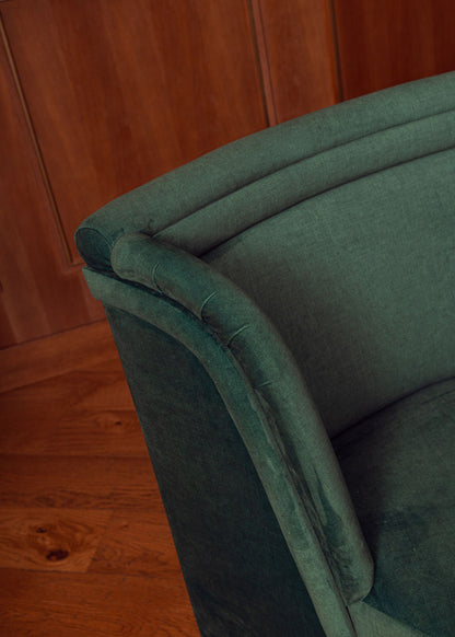 Banco curvado tapizado en terciopelo verde con patas de madera de haya.