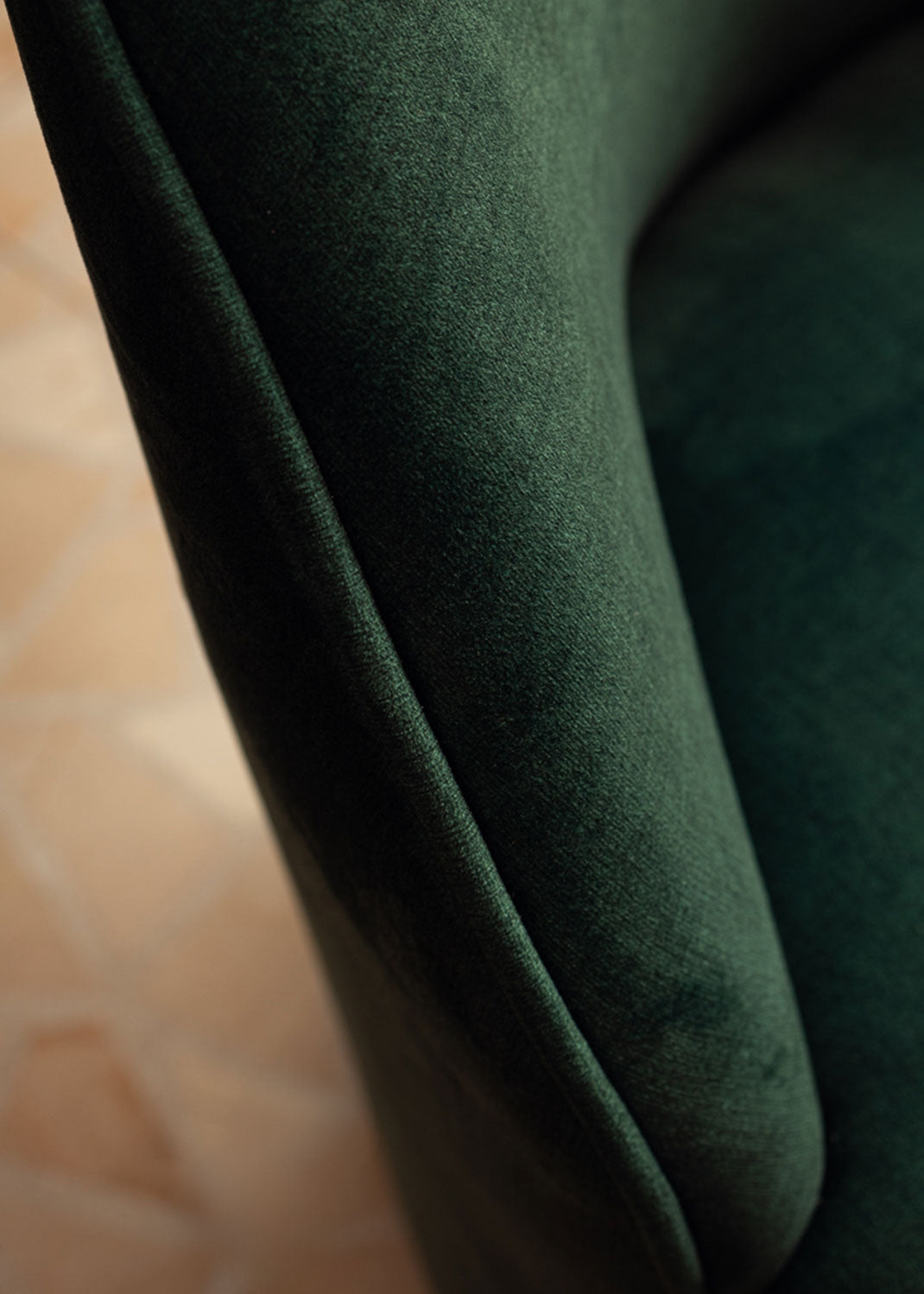 Butaca tapizada en terciopelo verde con zócalo dorado en la base.