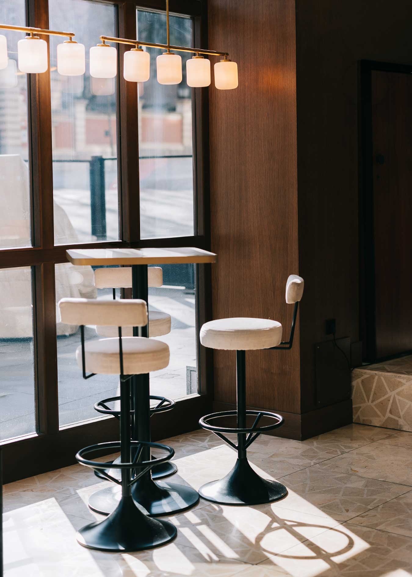 Taburete tapizado en tela beige con estructura de hierro acabado en negro.