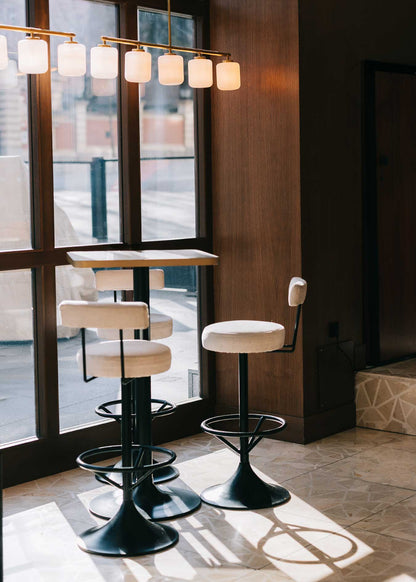 Taburete tapizado en tela beige con estructura de hierro acabado en negro.