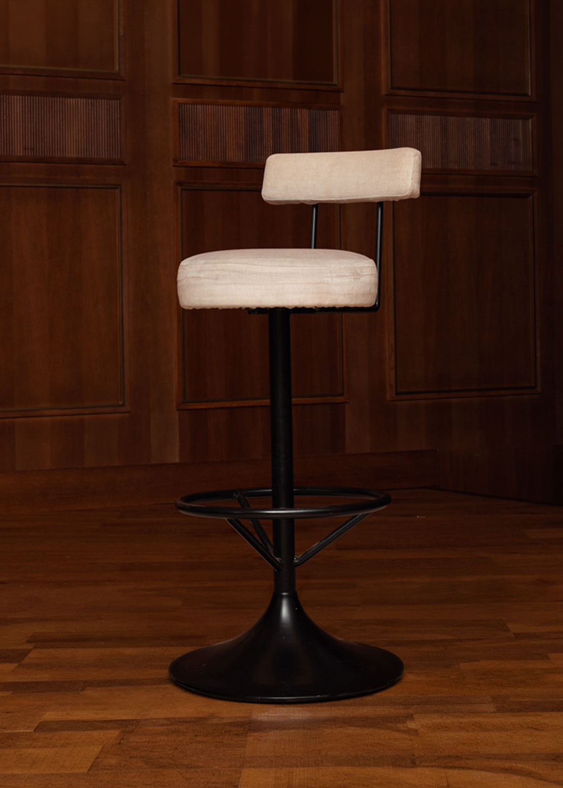 Taburete tapizado en tela beige con estructura de hierro acabado en negro.