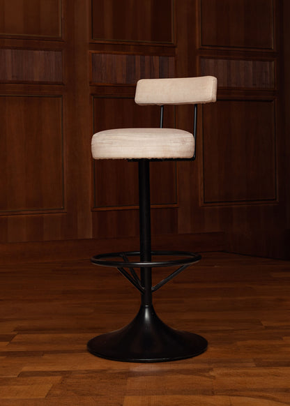 Taburete tapizado en tela beige con estructura de hierro acabado en negro.