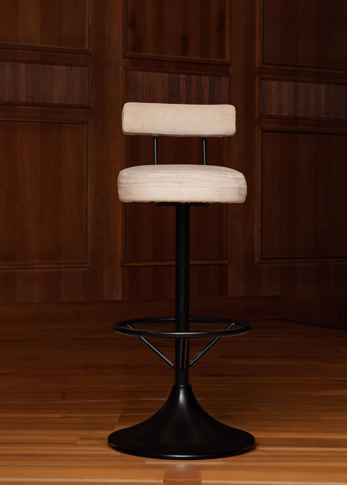 Taburete tapizado en tela beige con estructura de hierro acabado en negro.