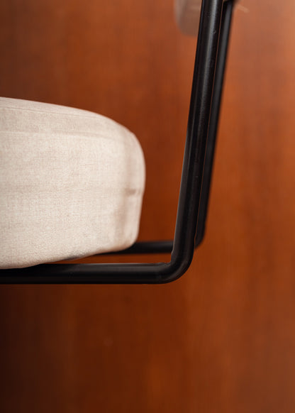 Taburete tapizado en tela beige con estructura de hierro acabado en negro.