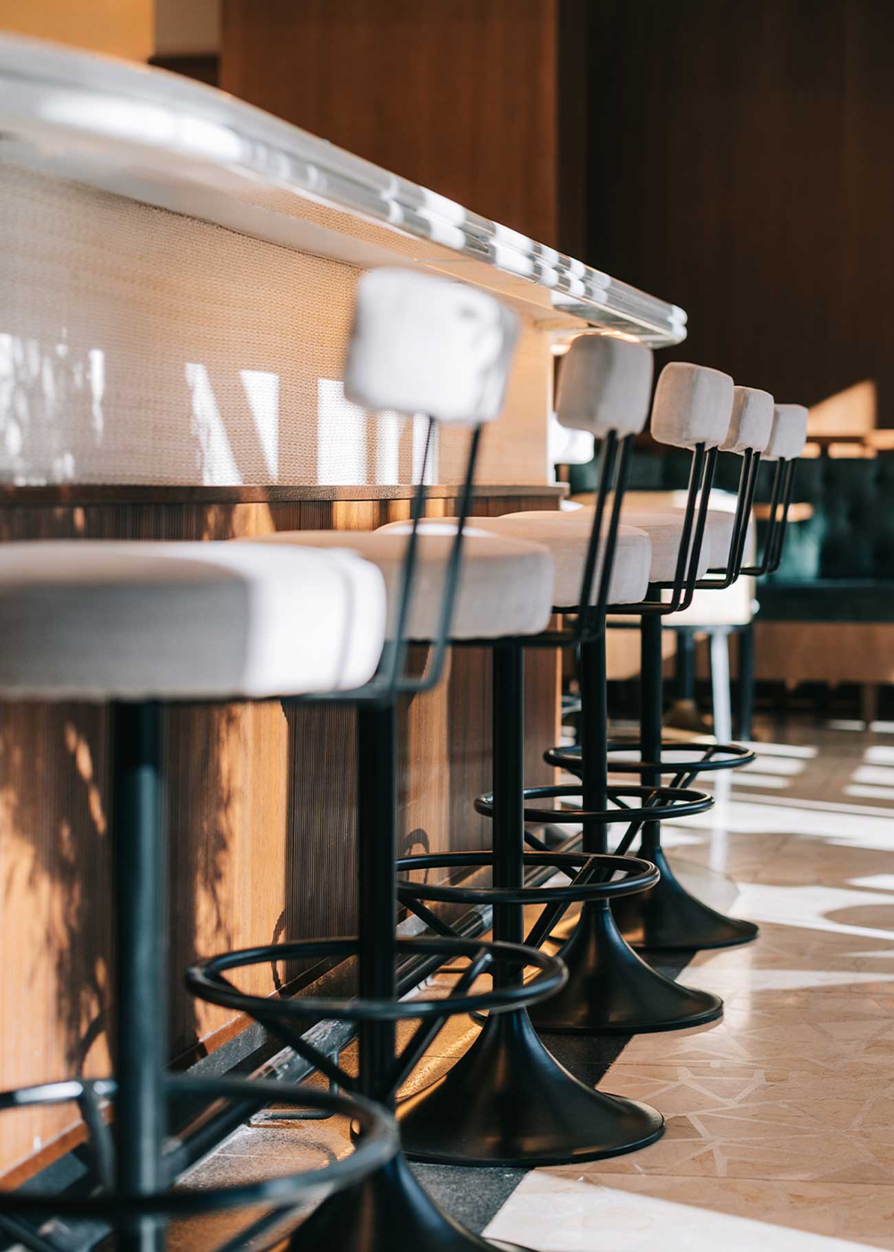 Taburete tapizado en tela beige con estructura de hierro acabado en negro.