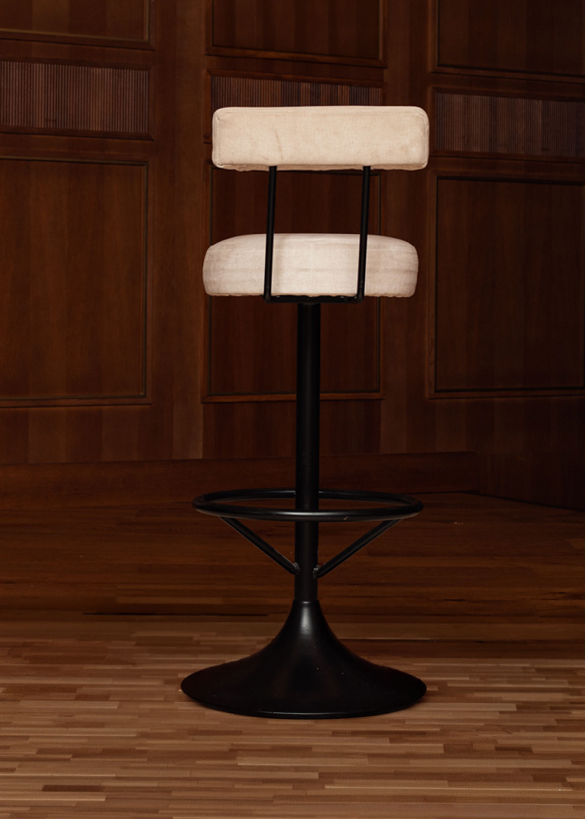 Taburete tapizado en tela beige con estructura de hierro acabado en negro.