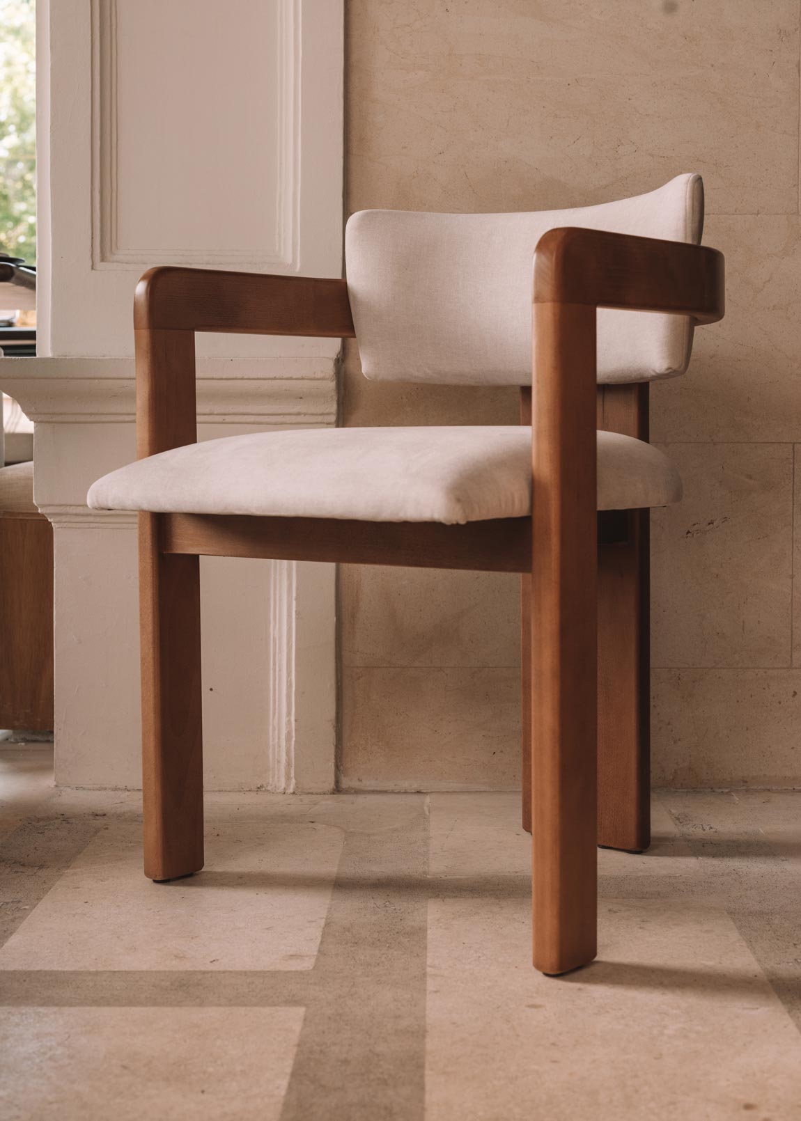 Silla de madera con reposabrazos tapizada en terciopelo beige