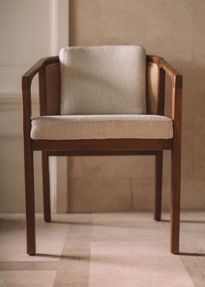 Silla de madera de haya con reposabrazos tapizada con una tela con textura en color beige