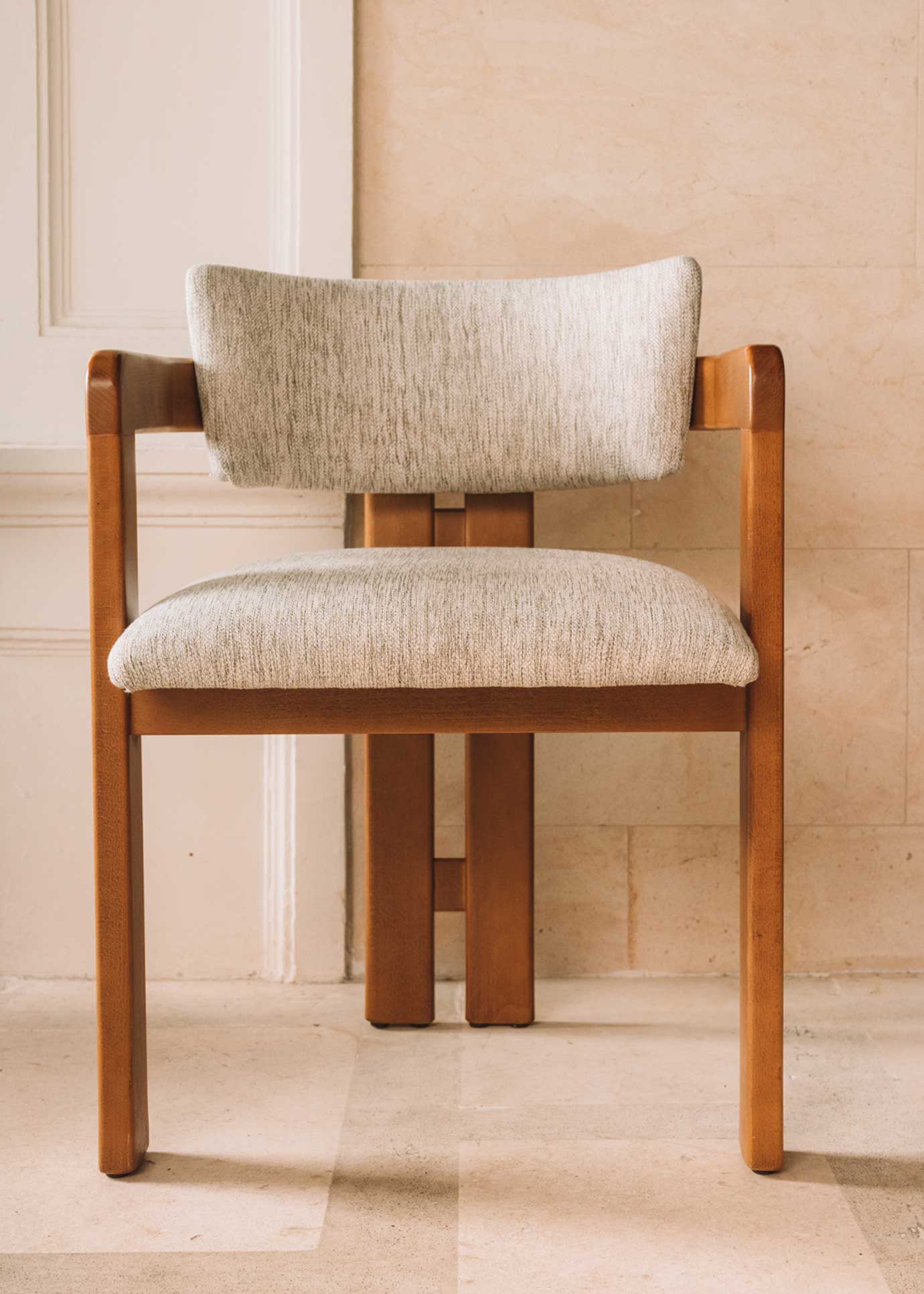 Silla de madera de haya con reposabrazos tapizada en tela jaspeada.