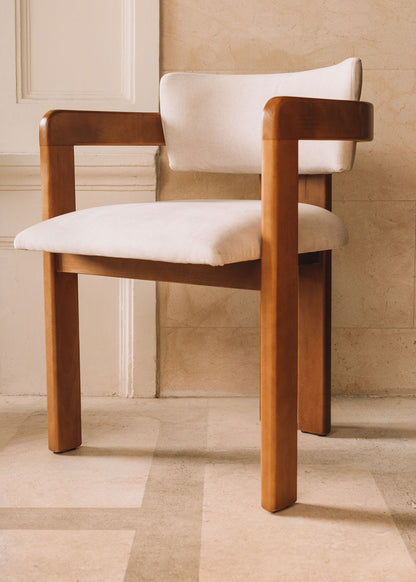 Silla de madera de haya con reposabrazos tapizada en terciopelo beige.