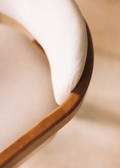 Silla de madera de haya con reposabrazos tapizada en terciopelo beige.