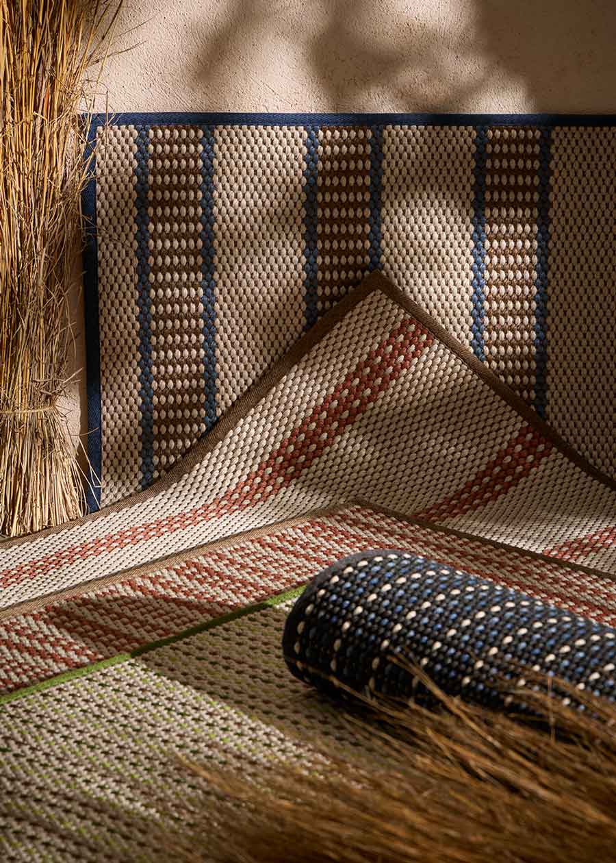 Alfombra fabricada en PET a partir de botellas de plástico recicladas de color beige con detalles en verde y elaborada en telar wilton de tejido plano.