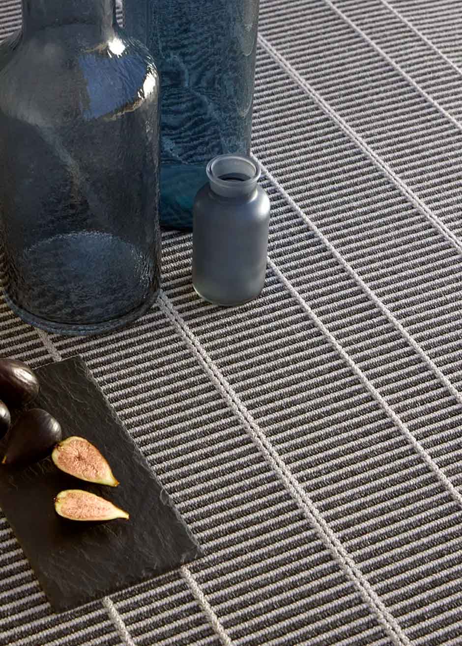 Alfombra fabricada en PET a partir de botellas de plástico recicladas de color gris azulado en telar wilton de tejido plano.