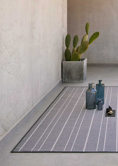 Alfombra fabricada en PET a partir de botellas de plástico recicladas de color gris azulado en telar wilton de tejido plano.