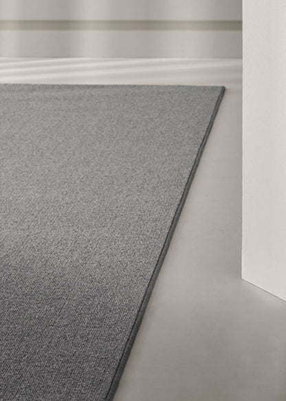 Alfombra fabricada con lana de color gris en telar tufting con superficie en bucle.
