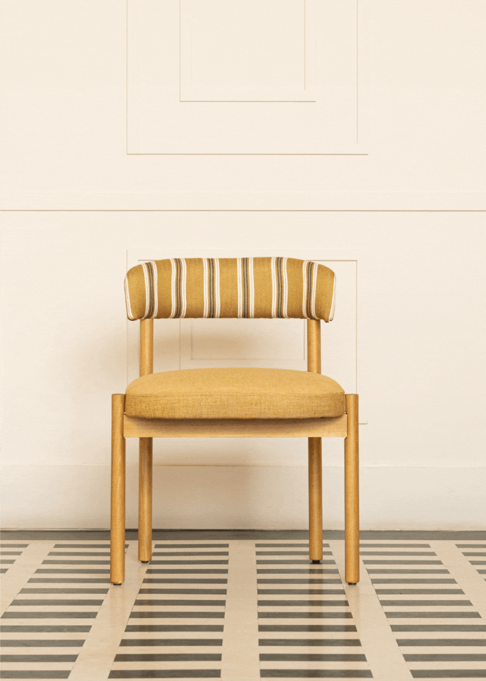 Silla de madera de haya con asiento tapizado en tela mostaza y respaldo con estampado de rayas.