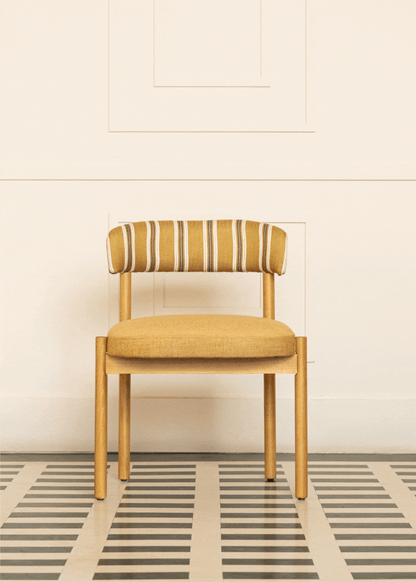 Silla de madera de haya con asiento tapizado en tela mostaza y respaldo con estampado de rayas.